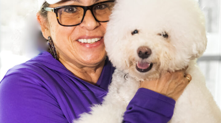 Smiling woman holding fluffy white dog.