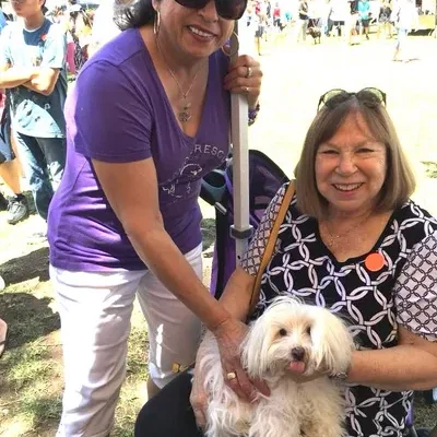 Two women smiling with small white dog.