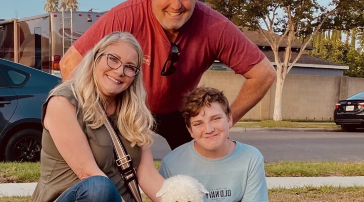 Family with dog sitting on grass outdoors.