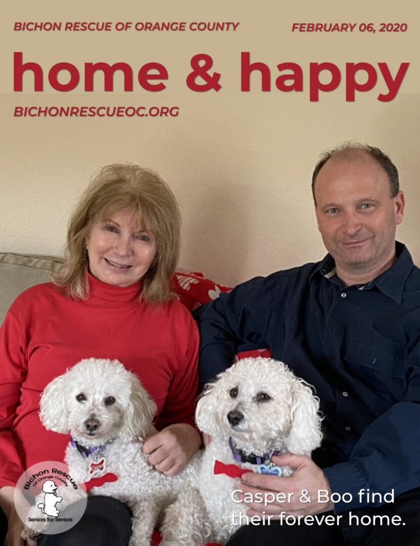 Couple smiling with two white dogs.
