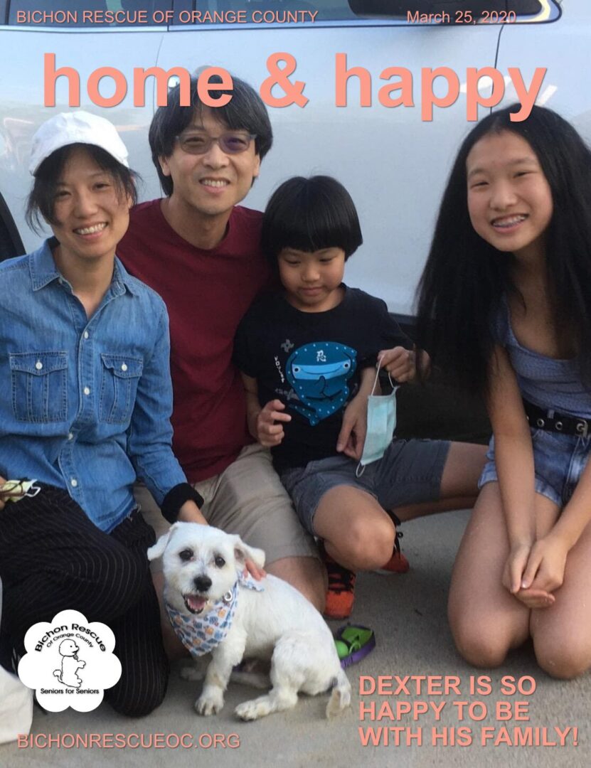 Family with dog sitting outdoors, smiling together.